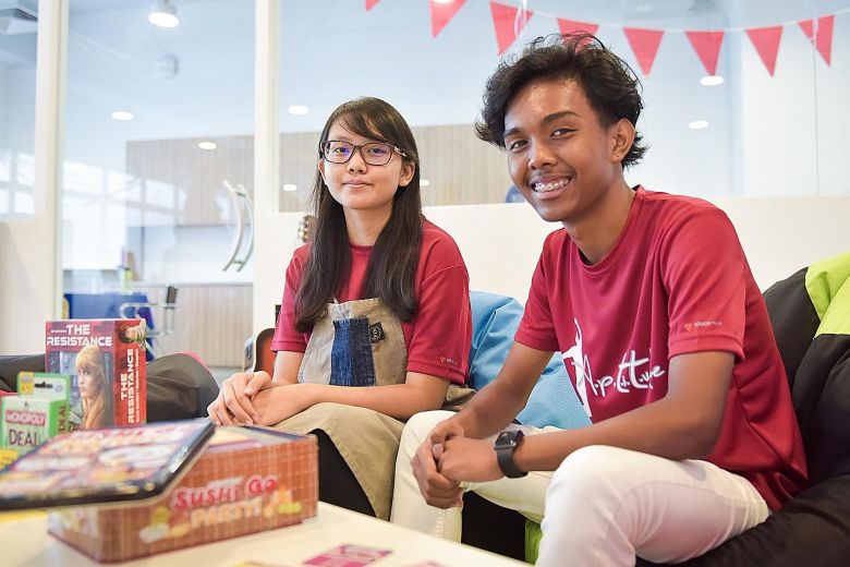 Two young people sitting on a couch, engrossed in a box of games, enjoying their leisure time together.