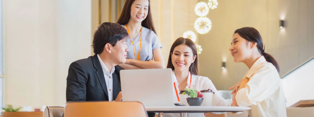 a group of young people looking and smiling at a laptop