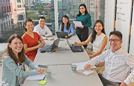 A group of young people in office attire sitting down and smiling