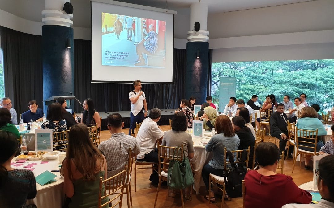 A gathering of individuals seated at tables within a room, engaged in conversation and activities.