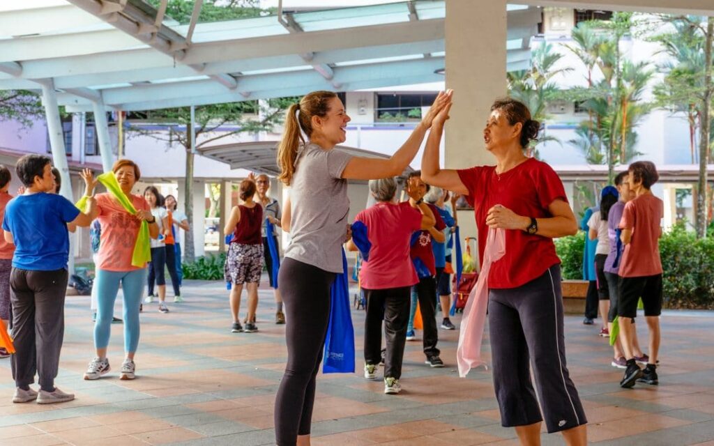 Group of individuals engaging in a leisure dance routine outdoors.