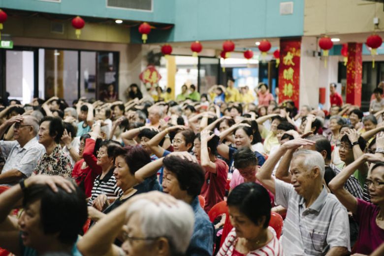 A room of elderly people doing head exercises