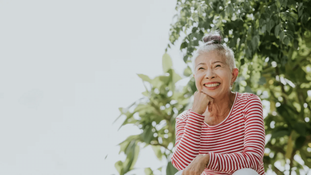 an old lady smiling in front of a tree