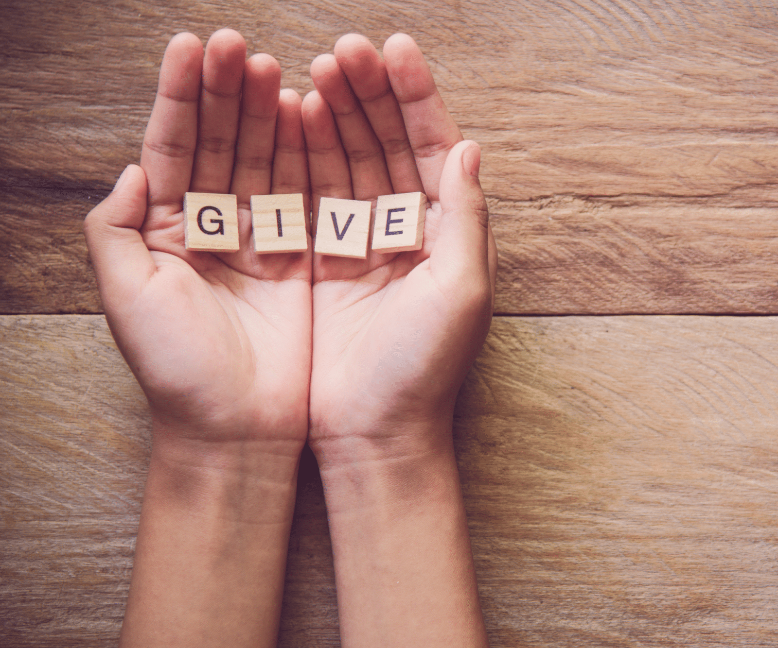 a hands holding small wooden blocks with letters on them