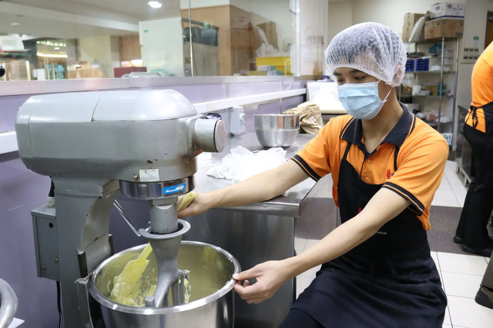 a person in a mask mixing food in a mixer