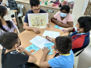 a group of children sitting around a table with books