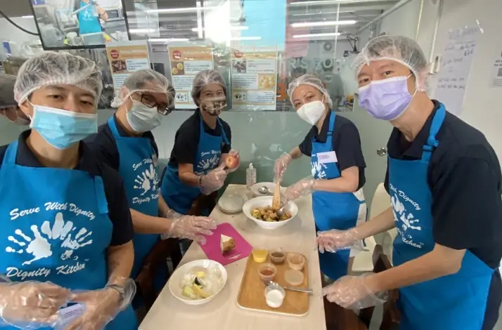 A group of people in hairnets preparing a dessert