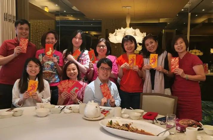 A group of people of different ages posing with red packets