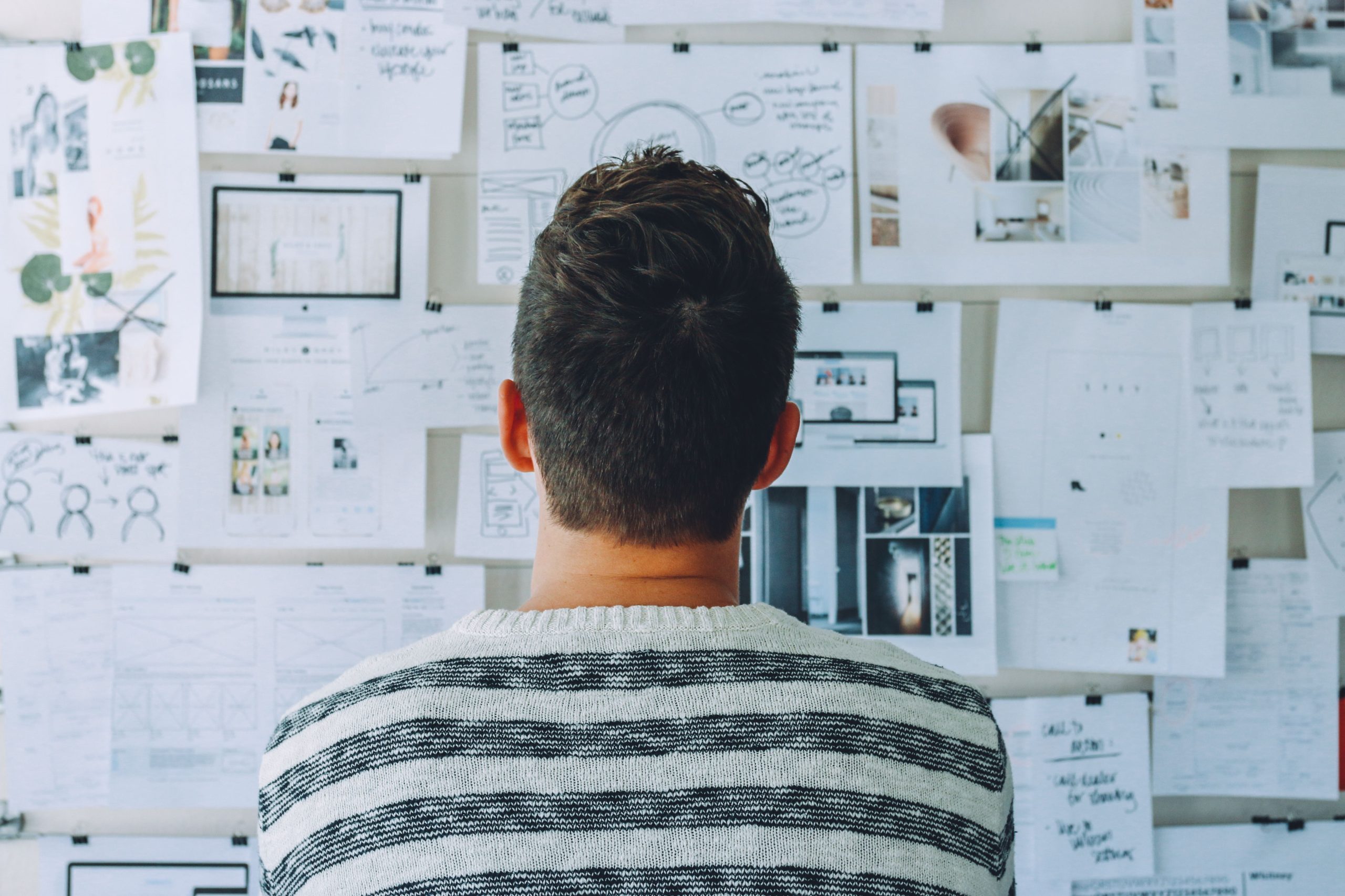 A guy looking at a board full of paper and clips