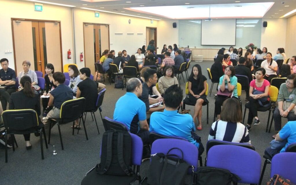 Group of individuals sitting in chairs indoors.