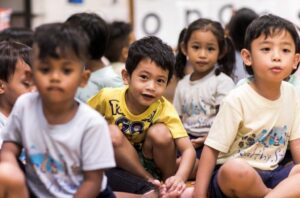 Young learners sitting on the classroom floor, participating in educational exercises.