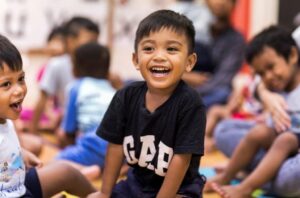 Children happily sitting on the floor, smiling and radiating joy.