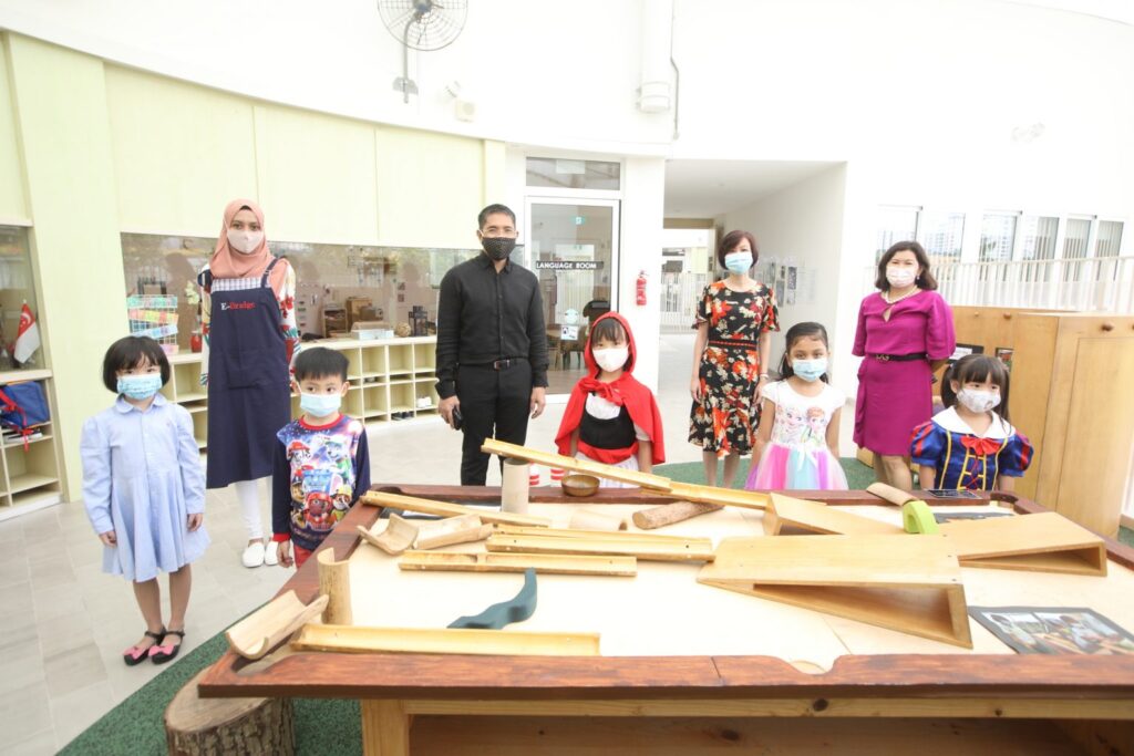 A diverse group of children and adults, all wearing masks, gather together in a united display of safety and responsibility.