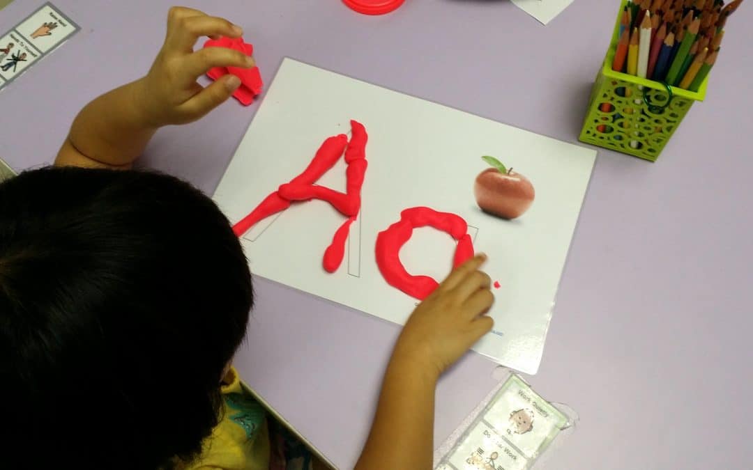 A child creatively arranges red and white paper to form letters, showcasing their artistic skills and imagination.