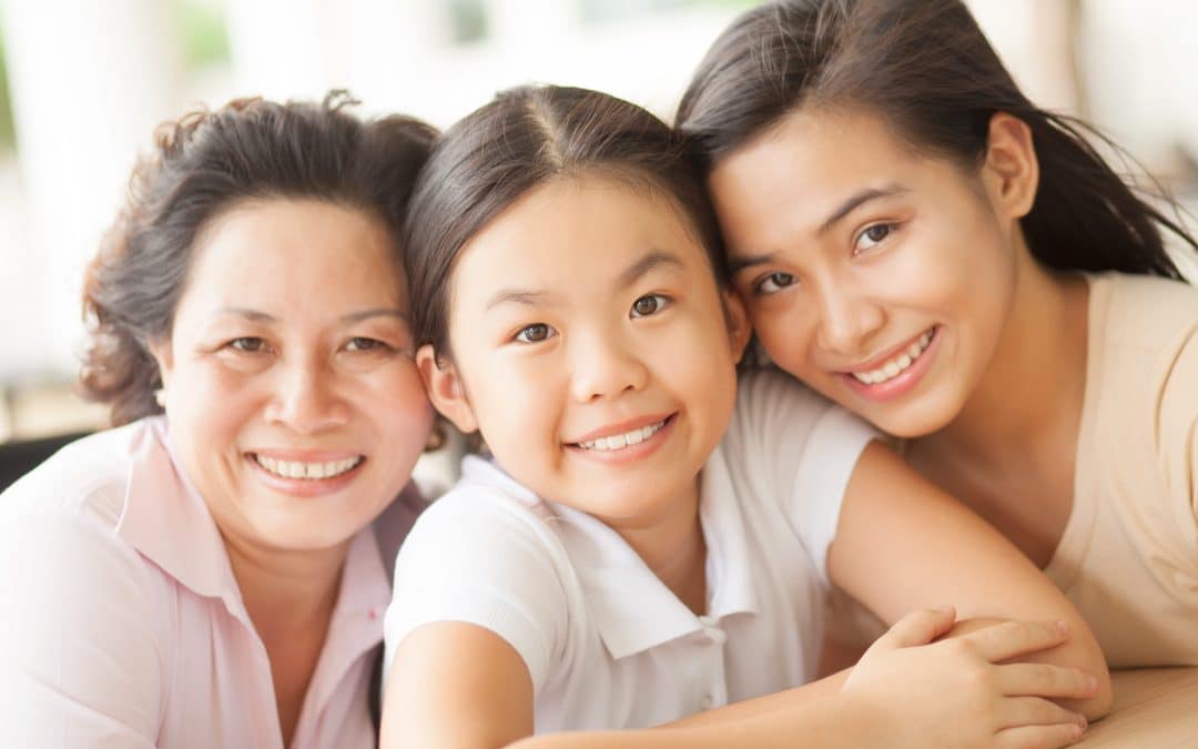 A woman and two girls, wearing joyful expressions, pose happily in front of the camera.