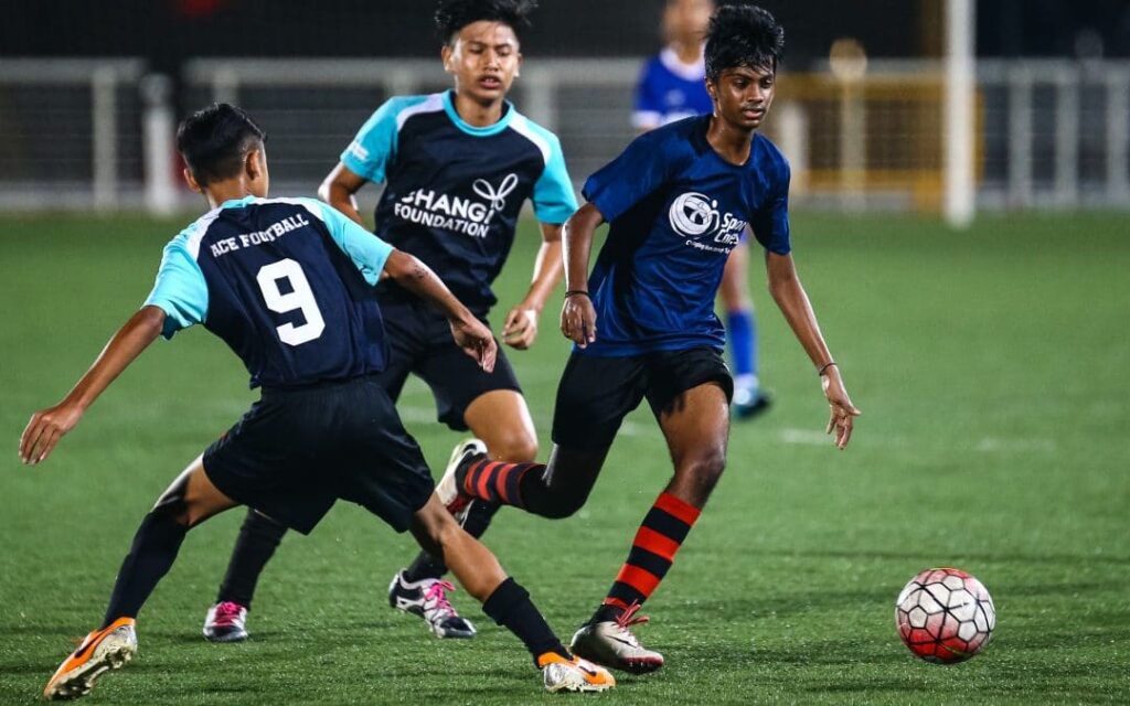 Three young men playing soccer on a field, displaying teamwork, agility, and passion for the sport.