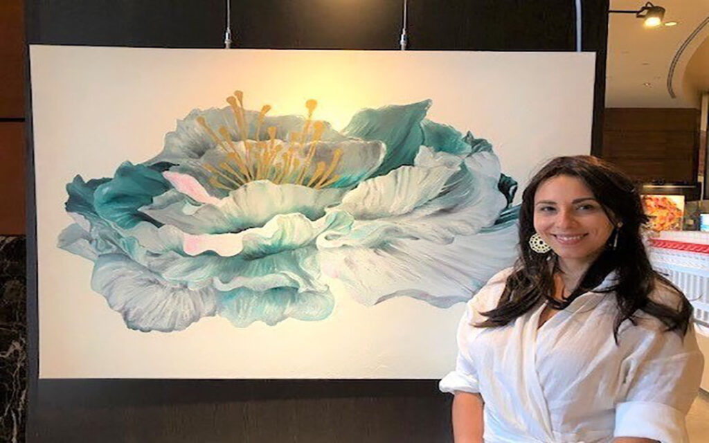 Woman standing next to a large flower painting.