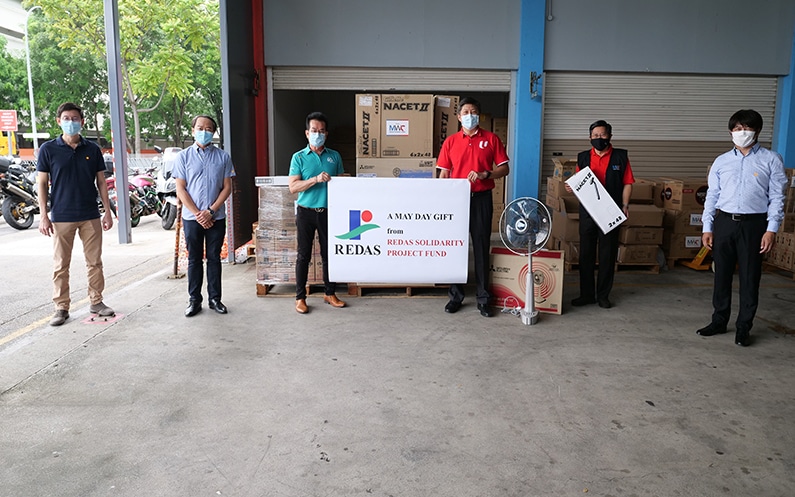 Group of individuals in front of warehouse with boxes.