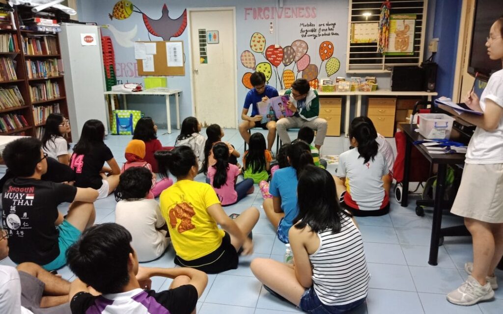 Children sitting in a circle, engrossed in a book, fostering a love for reading and learning together.