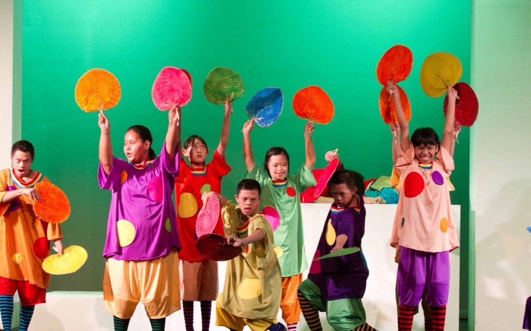 Children dressed in bright costumes holding props while performing on stage
