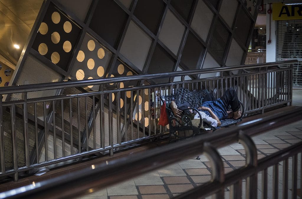 A man sleeping on a bench in a subway station.