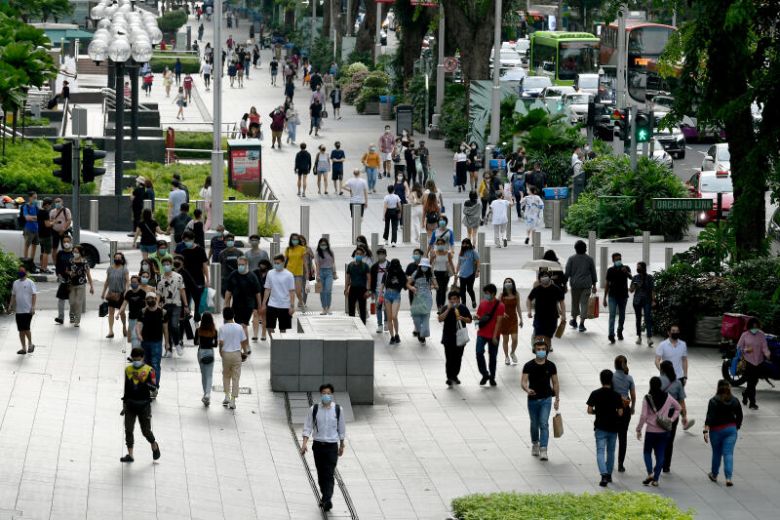 Many pedestrians walking on a bustling city street, surrounded by tall buildings and bustling activity.